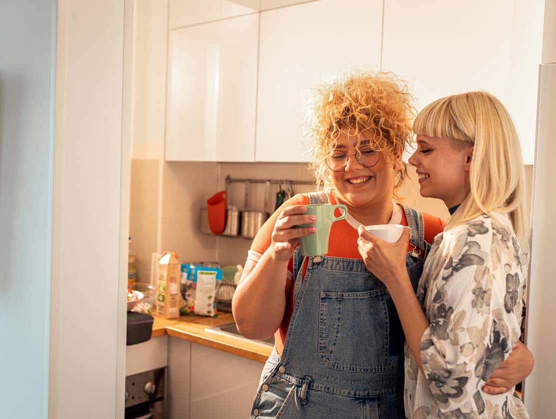 two women have coffee in their apartment